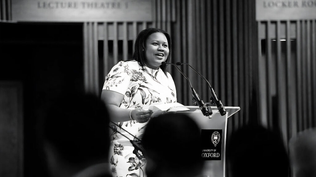 Fatou Wurie speaking at a podium during an event at the University of Oxford.